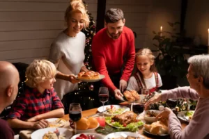 A festive dinner scene with multiple dishes, wine glasses, and a decorated Christmas tree, as family members share food joyfully.