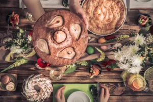 A beautifully set table with a fruit cake, pastries, salads, and flowers, capturing a warm, festive gathering.