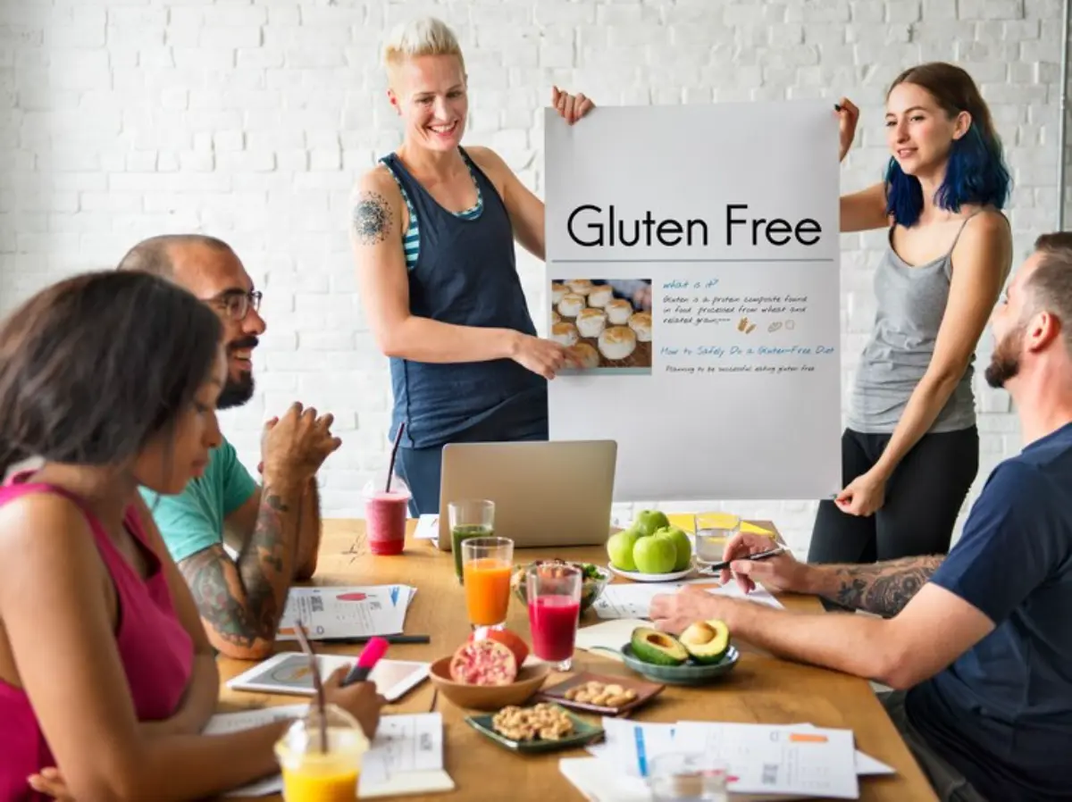 A group meeting focused on gluten-free diets, featuring a presentation and various healthy snacks on a wooden table.